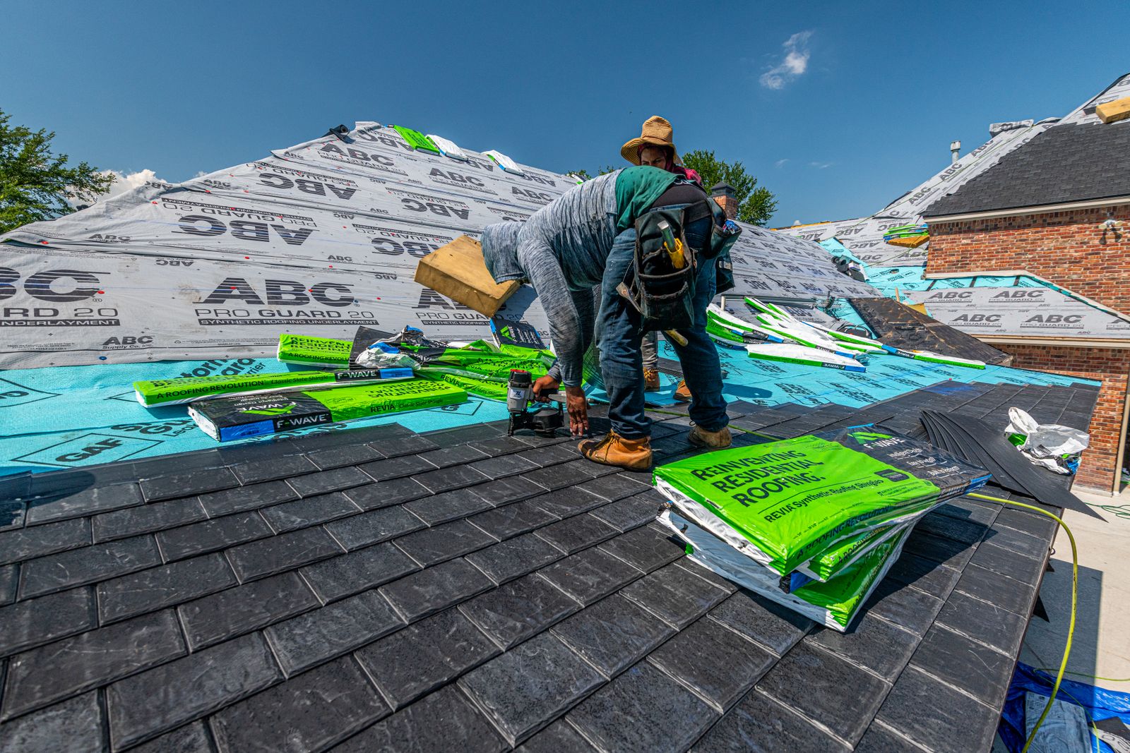 Roof installation in progress on a brick house