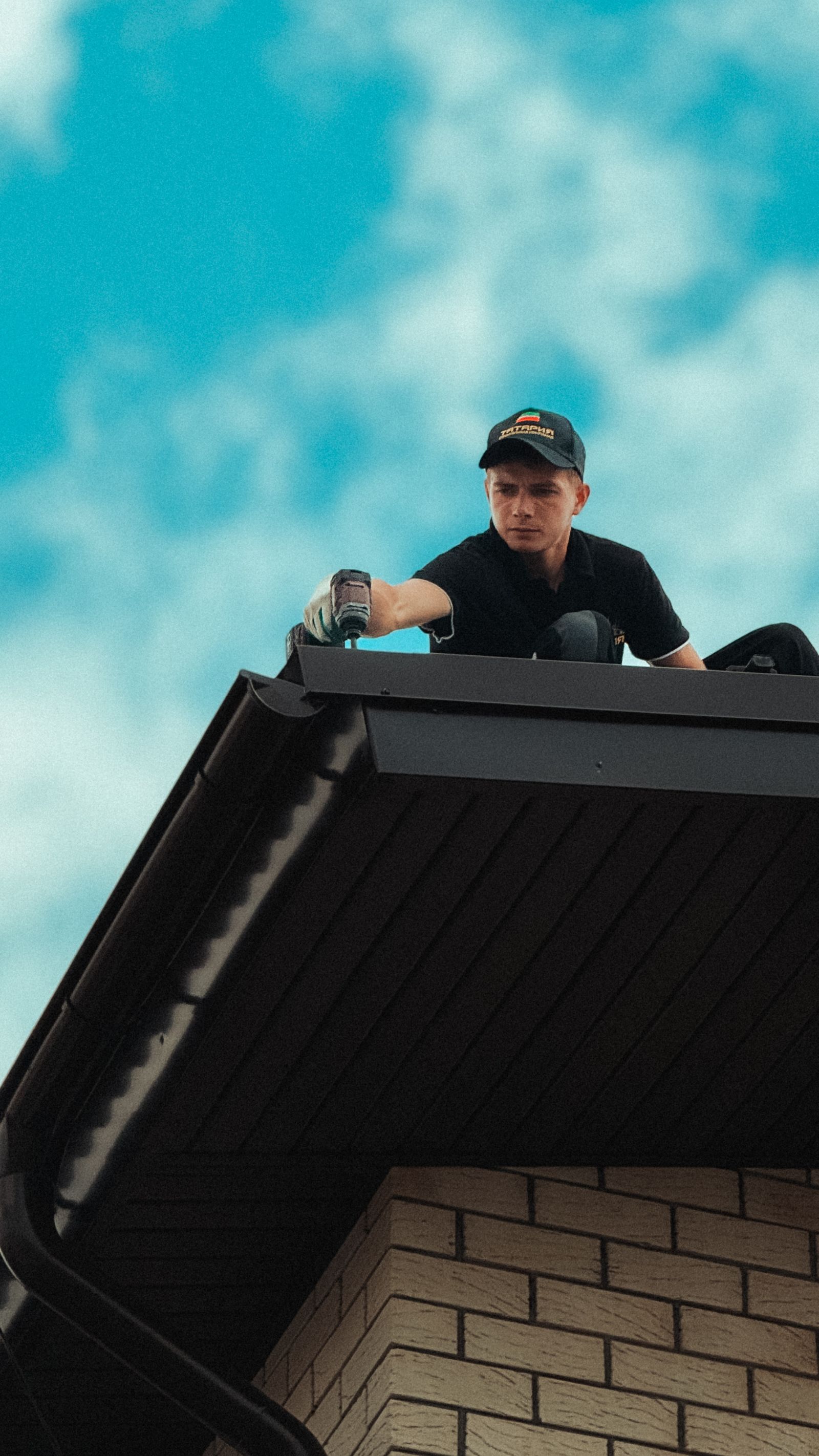 Roofer working on a house roof against a clear sky